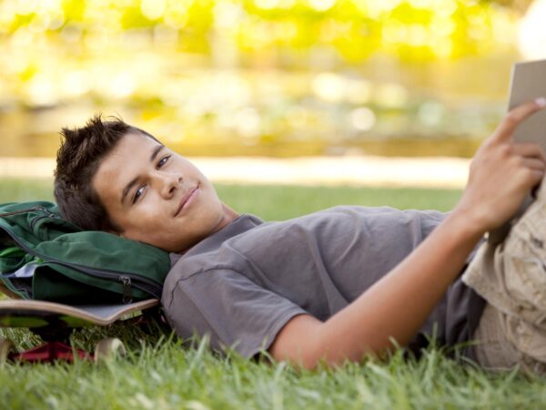stock-photo-student-with-skateboard-and-backpack-reading-in-the-grass-69133153